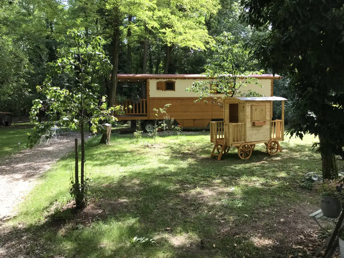 La roulotte en bois sous les arbres du jardin, en été