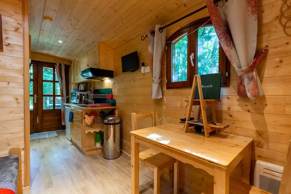 L’intérieur en pin clair : coin cuisine, table et fenêtre sur le jardin